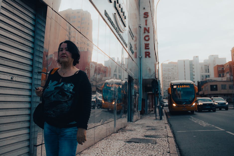 A woman walking down a street with a bus in the background